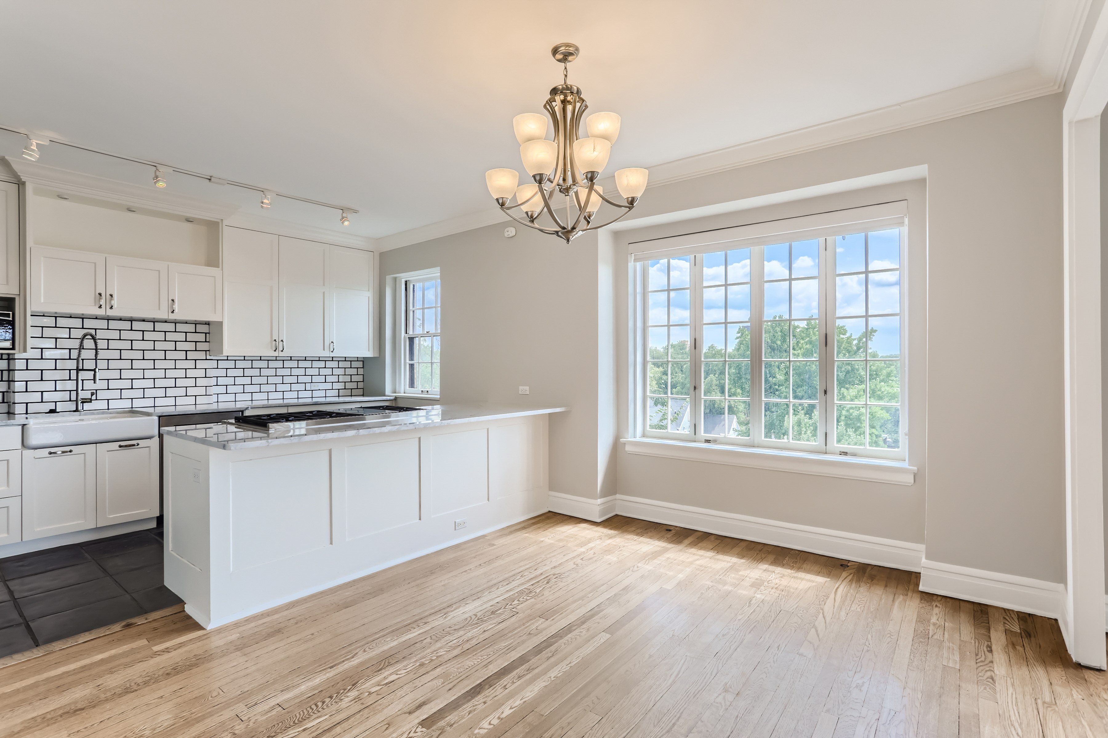 A kitchen with white cabinets and a wooden floor.